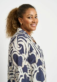 Navy blouse with cream abstract pattern, featuring a relaxed fit, button-down front, and soft fabric. Textured detail adds visual interest.
