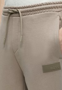 Pantalon de jogging beige avec taille à cordon, poche latérale et patch logo "BOSS" en caoutchouc sur la cuisse.