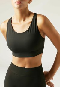 Schwarzes sportliches Crop-Top aus dehnbarem Material, mit weitem Rundhalsausschnitt und breiten Trägern für Unterstützung.