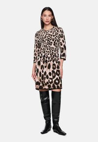 Kleid mit Leopardenmuster, dreiviertelärmlig, aus leichtem Stoff, mit rundem Halsausschnitt und ausgestelltem Schnitt, kombiniert mit glänzenden schwarzen Stiefeln bis zum Knie.
