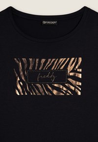 Maglietta nera con stampa a righe di zebra dorate. Il design presenta un'etichetta rettangolare con il nome "freddy" in corsivo.