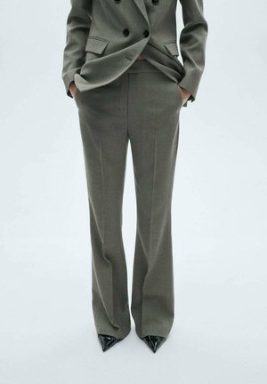 Pantaloni de costum verzi, croiți, dintr-un material texturat. Se remarcă prin talie înaltă, picioare late și dungi fine. Asortați cu pantofi negri ascuțiți.