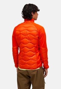 Giacca arancione con design trapuntato imbottito sulla schiena, maniche lisce a contrasto, colletto alto e vestibilità atletica.