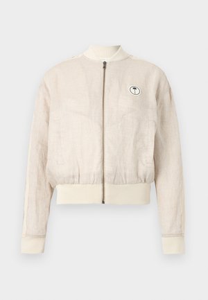 Bézs lenvászon bomber dzseki elülső cipzárral, bordázott mandzsettákkal és szegéllyel, oldalzsebekkel, valamint egy kis kerek folttal, melyen egy pálmafa látható a mellrészen.