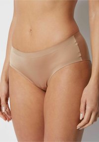 Beige naadloze hipsterondergoed gemaakt van gladde stof met een gemiddelde taillehoogte, met een eenvoudig ontwerp en zonder zichtbare naden.
