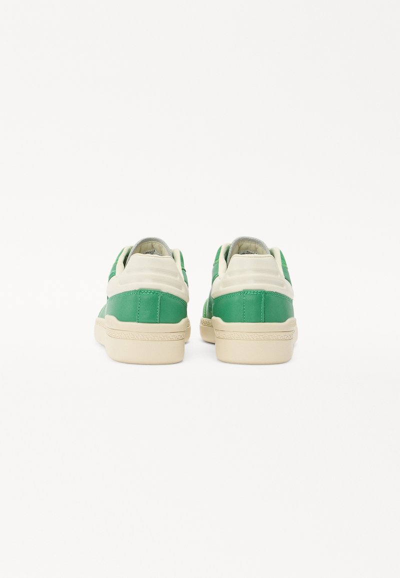 Sneaker verde e crema con finitura liscia, dotate di suola testurizzata e tallone imbottito. Design minimalista, con pannelli di colore a contrasto.