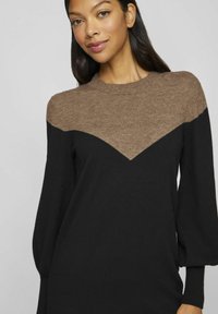 Pull color block noir et marron avec un motif en chevron, col rond et longues manches bouffantes, fabriqué dans un tissu doux.