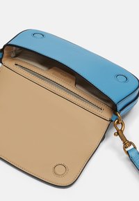 Niebieska skórzana torba na ramię z beżowym wnętrzem, wyposażona w zamykaną kieszeń, złotą okuciami i zapięciem na klapę u góry.