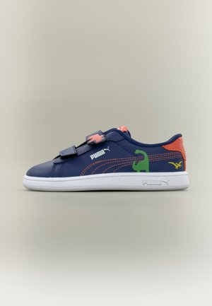 Marineblå Puma-sneaker med orange accenter, grønne og gule dinosaurmotiver, hvid sål og velcrolukninger på en neutral baggrund.