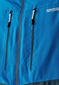 Veste de plein air bleue avec deux poches zippées verticales, tirettes de fermeture éclair blanches et logo "Regatta Great Outdoors" sur la poitrine.