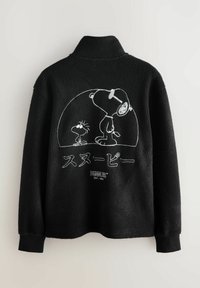 Schwarze Fleecejacke mit weißem Umriss von Snoopy und Woodstock in einer Kuppel, japanischem Text und Peanuts-Logo auf dem Rücken.