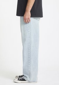 Lys blå rettskårne jeans laget av denim, med side lommer og et enkelt design. Kombinert med svarte og hvite joggesko.