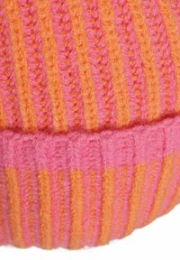 Close-up of knitted fabric with vertical orange and pink stripes and a folded ribbed edge at the bottom.