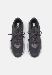 Ciemnoszare buty sportowe z siateczkową cholewką, kontrastowymi szarymi akcentami i teksturowaną podeszwą. Posiadają sznurowadła z odblaskowymi detalami.