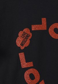 Černé tričko s velkým červeným třpytivým nápisem tvořícím slovo "LOVE" a červeným třpytivým mráčkem s textem "LOVE MOSCHINO."