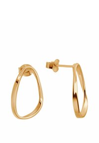 Złote kolczyki w kształcie dużych kół o płynnej, wydłużonej formie. Projekt charakteryzuje się gładką teksturą oraz bezpiecznym zapięciem na sztyft, co ułatwia noszenie.