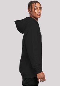 Black hoodie with a front pocket, adjustable drawstring hood, and ribbed cuffs. Features a visible logo on the chest area.