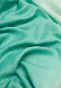 Tissu léger et texturé en vert aqua, présentant une apparence douce et légèrement translucide avec des variations subtiles de couleur et de tissage.