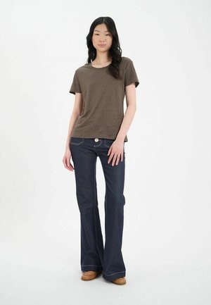 T-shirt marron à manches courtes associé à un jean évasé bleu foncé. Le jean présente des coutures blanches et un détail de bouton à l'avant.