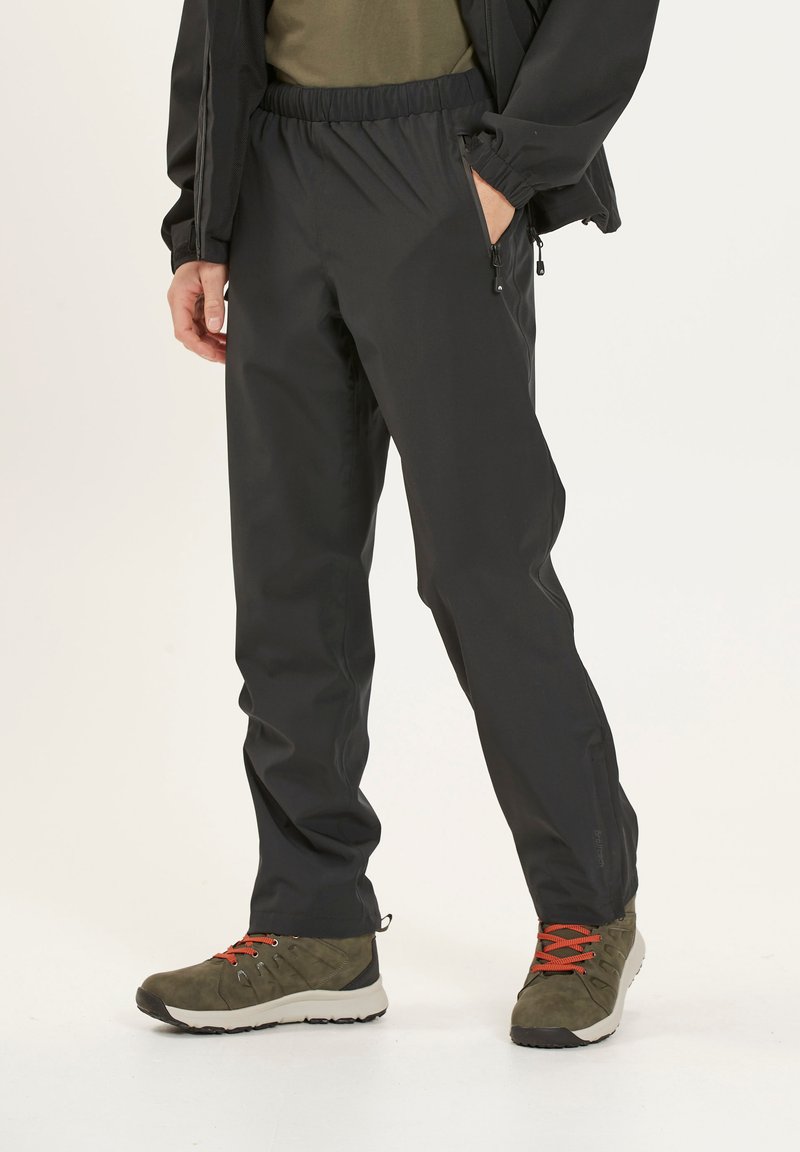 Sorte vandtætte bukser med en afslappet pasform, elastisk talje og sidelommer. Sammen med olivengrønne vandrestøvler med orange detaljer.