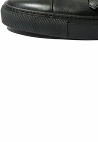 Czarne skórzane trampki z teksturowaną czarną gumową podeszwą, charakteryzujące się gładką cholewką, stonowanym szwem i brakiem widocznych elementów sprzętowych lub akcentów.