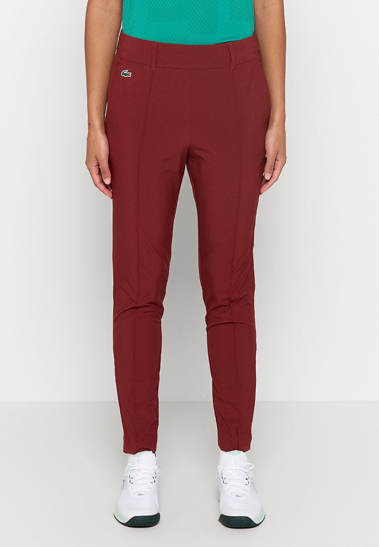 Pantalons de sport bordeaux à coupe slim, fabriqués en tissu extensible. Dotés d'un logo discret sur la hanche et d'une texture lisse.