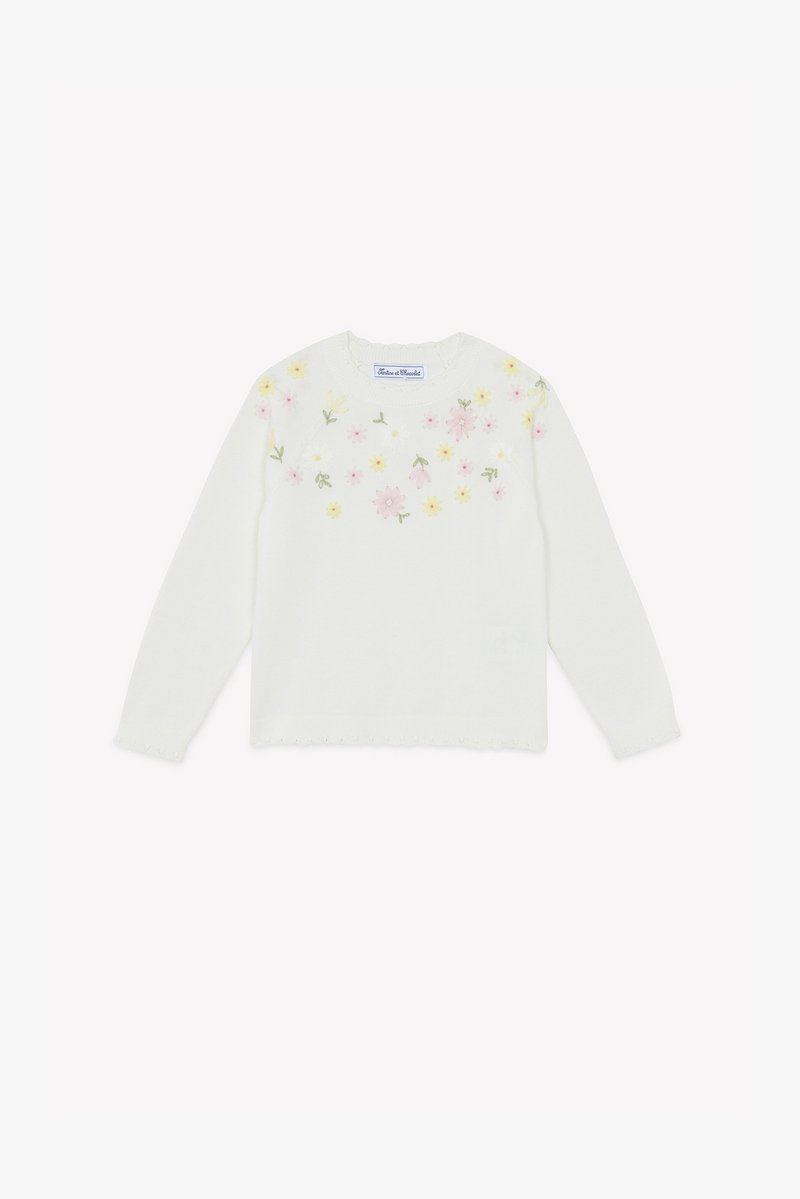 Pull en tricot blanc à manches longues, orné de broderies florales colorées sur la poitrine et d'un ourlet festonné décoratif.