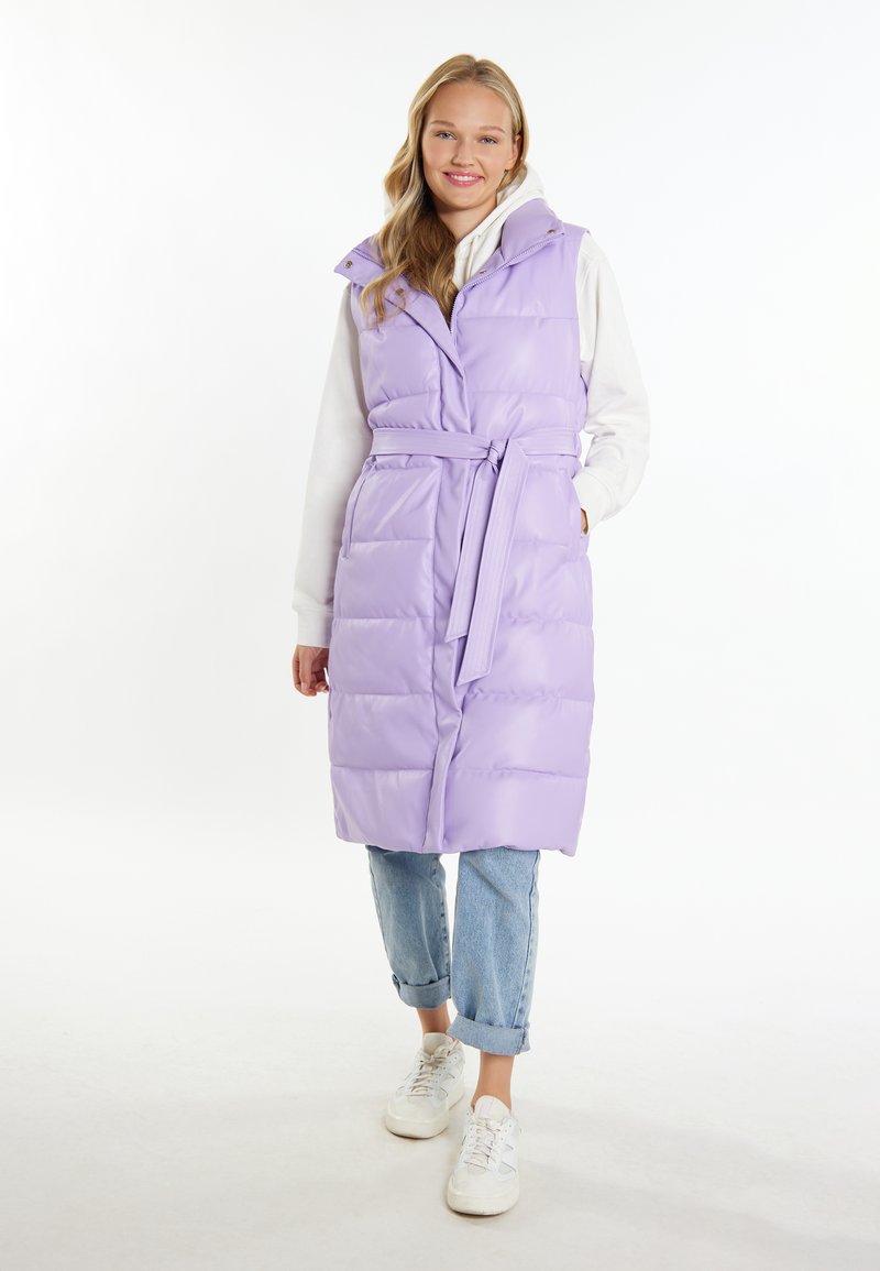 Vest padded de culoare violet deschis, cu o curea, cusături verticale și guler pliat, purtat peste un hanorac alb și asociat cu blugi denim cu manșete și adidași.