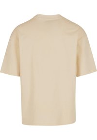 T-shirt en coton beige à manches courtes, col rond et coupe décontractée. Dos sans coutures, sans étiquettes ni motifs visibles. Texture douce.