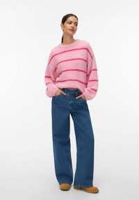 Pull rose duveteux avec des rayures horizontales rose foncé, associé à un jean large taille haute en denim bleu et des bottines marron.