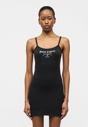 Kvinde iført en tætsiddende sort, ærmeløs minikjole med tynde stropper og hvid tekst på brystet, der lyder "Palm Angels Los Angeles Milano".