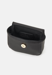 Svart läderpung med rundad form, förkunnad med ett guldknäppe och en minimalistisk inredning.