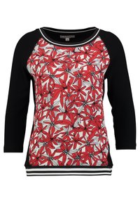 Zwart langemouwtop met een rood en wit bloemenpaneel aan de voorkant en een gestreepte zwart-wit zoom en halslijn.
