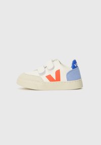 Hvite sneakers med borrelås, med en rød 'V' logo og blå semsket skinn detaljer på hælen. Gummisåle, avrundet tå og teksturert overflate.