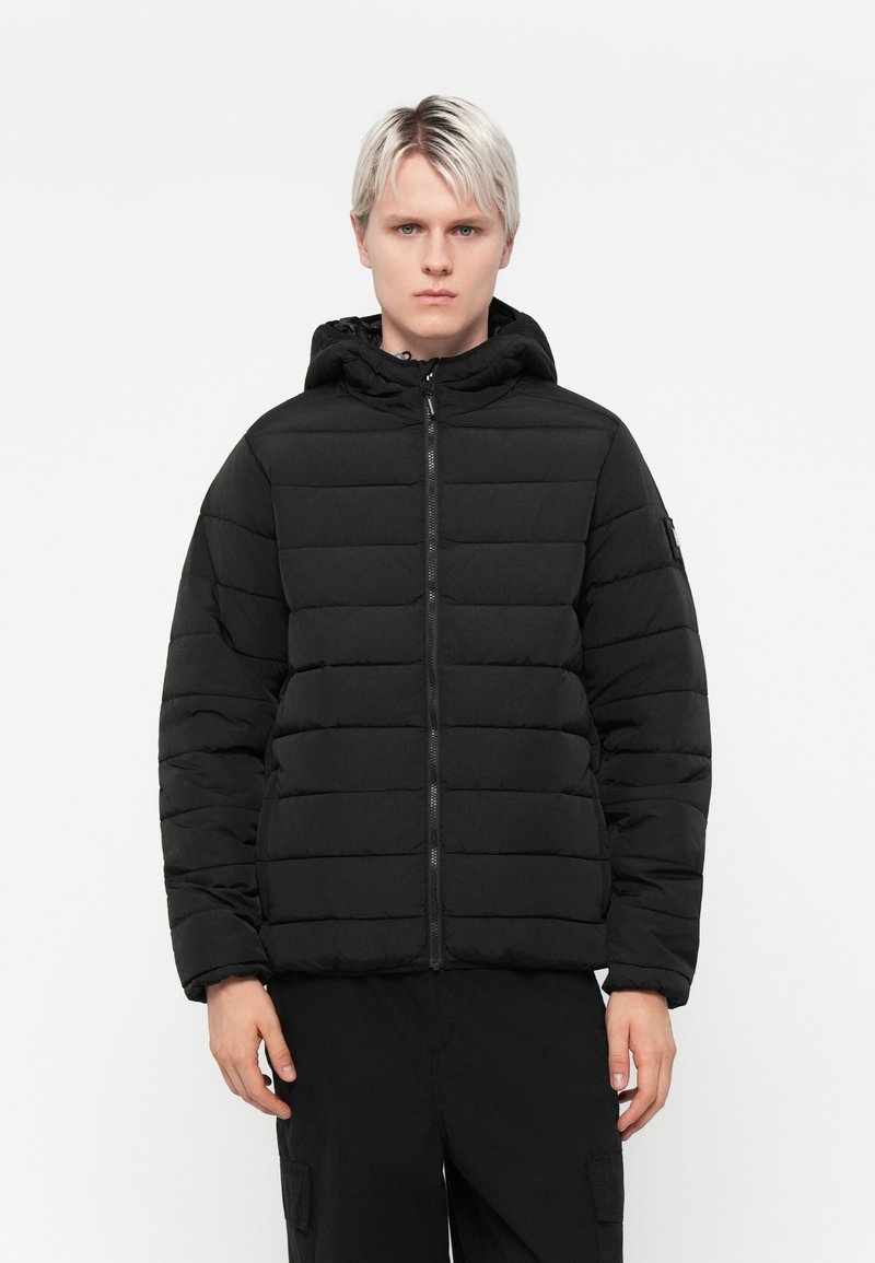 Sort pufferjakke med hætte, der har et kviltet design, frontlynlås og ribbede manchetter. Fremstillet af glat, let materiale.