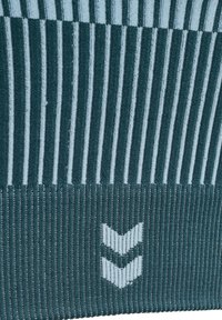 Donkergroene gebreide stof met verticale lichtgroene strepen en twee witte chevronvormen gecentreerd nabij de onderkant.