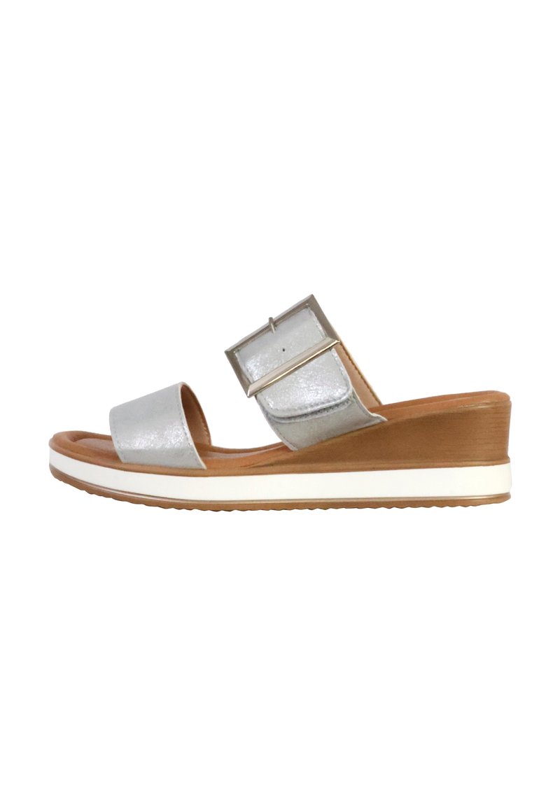 Wedge sandal with a silver metallic synthetic upper, two wide straps, and a contrasting white rubber sole. Flat sole with light brown accents.