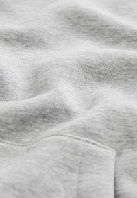 Gray sweatshirt fabric with a soft, textured surface; visible heather pattern and a slight stretch; features a pocket on the left side.
