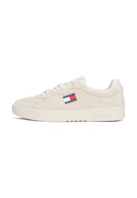 Zapatillas beige con ante y tejido texturizado, con cordones blancos y un parche de logo en rojo, blanco y azul en el lateral. Suela plana.