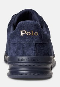 Semišová teniska námořnické modré barvy s kulatým tvarem, zdobená zlatým logem "Polo" a vyraženým nápisem "Ralph Lauren" na boku. Texturovaná podrážka pro lepší přilnavost.