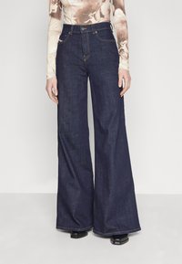 Dark blue wide-leg jeans with a high waist, finished with contrasting orange stitching, and a button closure at the front.