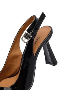 Scarpa con tacco alto in vernice nera, con finitura lucida, cinturino alla caviglia regolabile e un design unico del tacco geometrico.