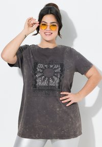 Mørkegrå oversized t-shirt med distressed tekstur og frontgrafik. Har en rund halsudskæring og korte ærmer.