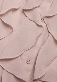Blush-pinke Bluse mit gerafftem Frontdesign, transparenter Stoffstruktur und runden Knöpfen. Verfügt über subtile Nähte an den Kanten.