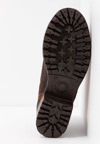 Ruskeat nahkasaappaat, joissa on kestävä kumipohja, syvät urat ja keltaiset ompeluseikat. Koko 37 painettu pohjaan.