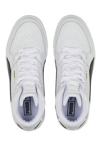 Valged nahast spordijalatsid mustade aktsentidega, millel on tekstuuriga pealis, perforatsioonidega varvaste ala ja valged paelad. Nähtav kuldne logo detail.