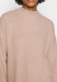 Maglione lavorato a maglia di un rosa morbido, con colletto alto, vestibilità ampia e tessuto testurizzato con motivo a coste.