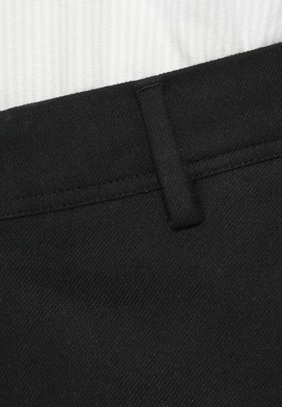 Pantalon en tissu noir avec une surface texturée, doté d'une taille plate, de passants de ceinture et de coutures près de la taille.