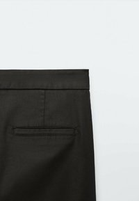 Pantalon noir à texture lisse, doté d'une ceinture plissée et d'une poche arrière rectangulaire avec une finition de couture discrète.