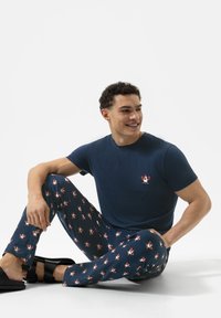 Marine katoenen T-shirt met korte mouwen en geborduurd ontwerp. Bijpassende pyjamabroek met een kleurrijk kreeftenpatroon en zwarte sandalen.